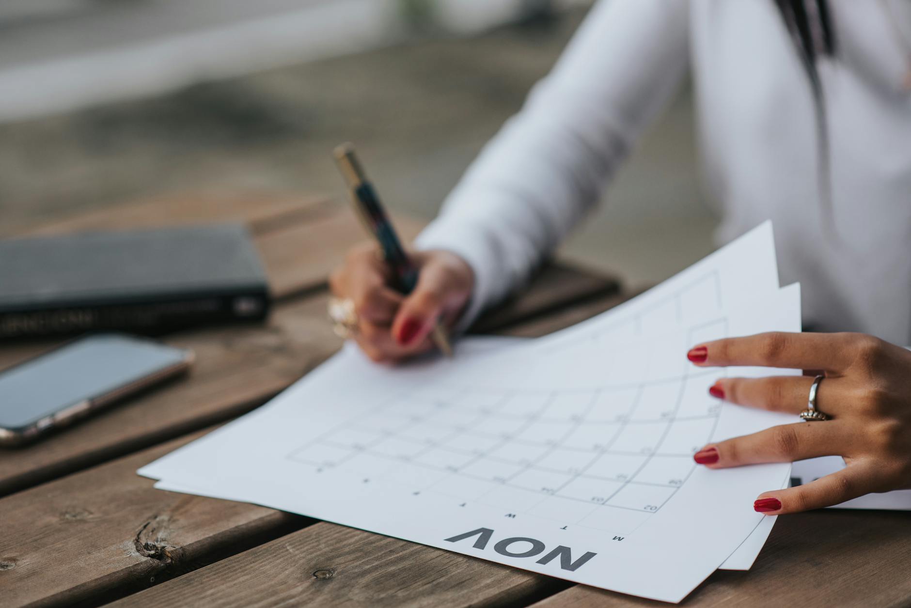 crop woman filling calendar for month. taking charge of 2024's second half