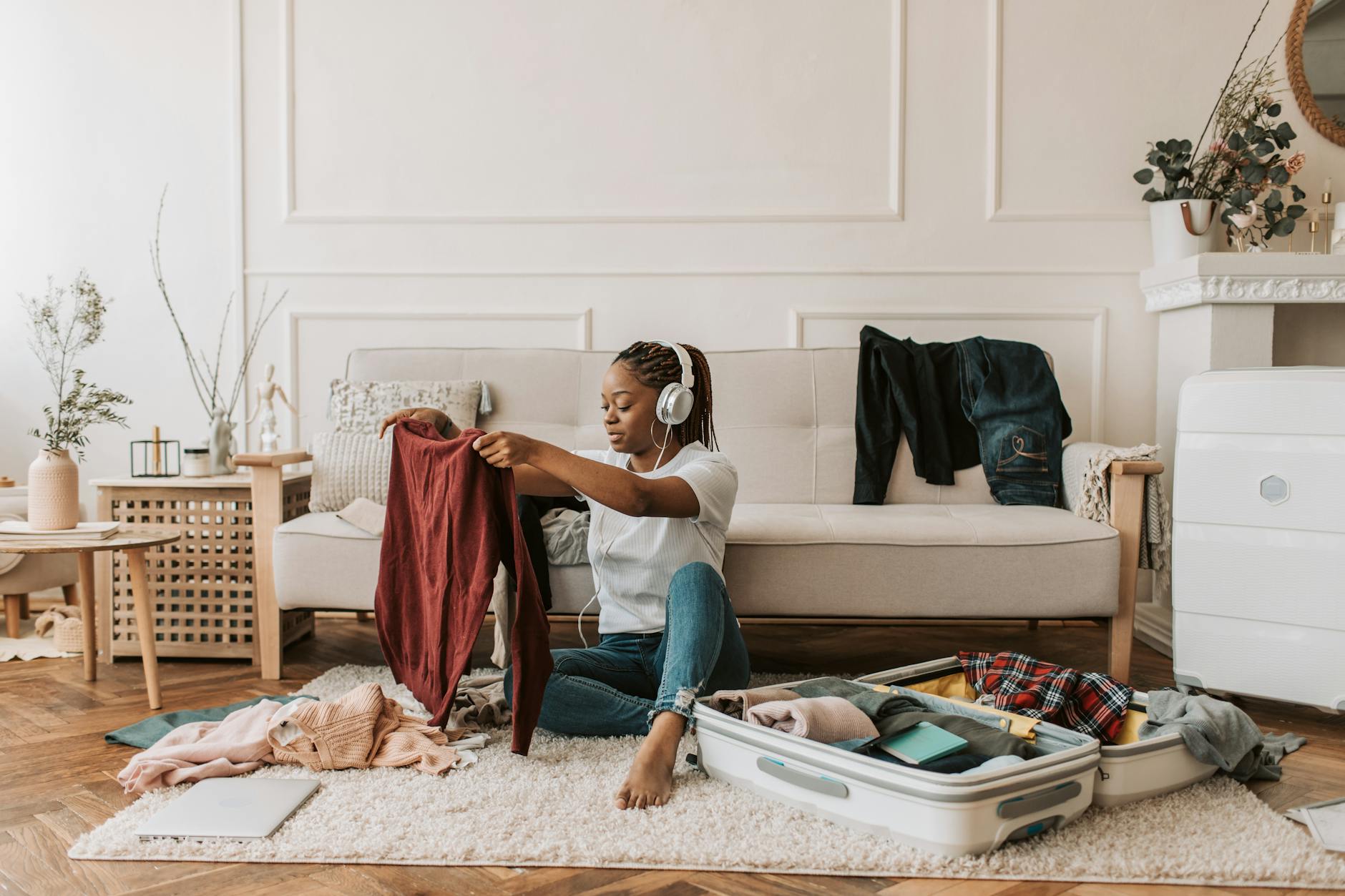a woman listening on her headphones while packing. oversized suitcase article
