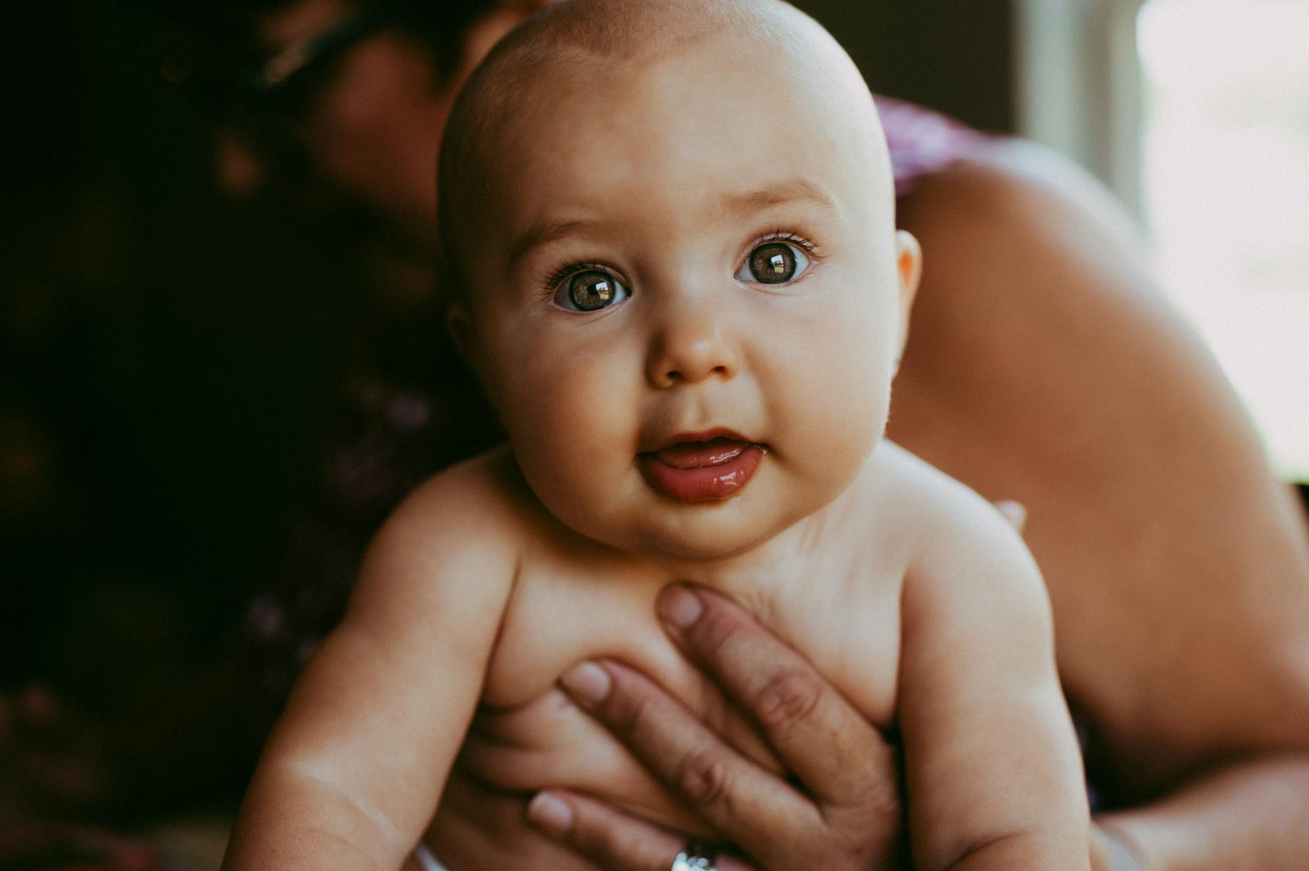 anonymous woman embracing cute baby in bedroom