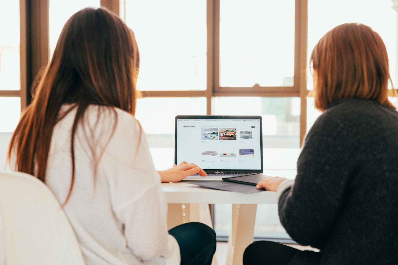 effective delegation - two women talking while looking at laptop computer