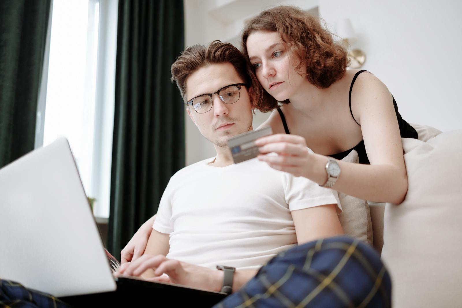 A young couple using a laptop and credit card for online shopping indoors. Why Closing Credit Cards Isn’t a Disaster