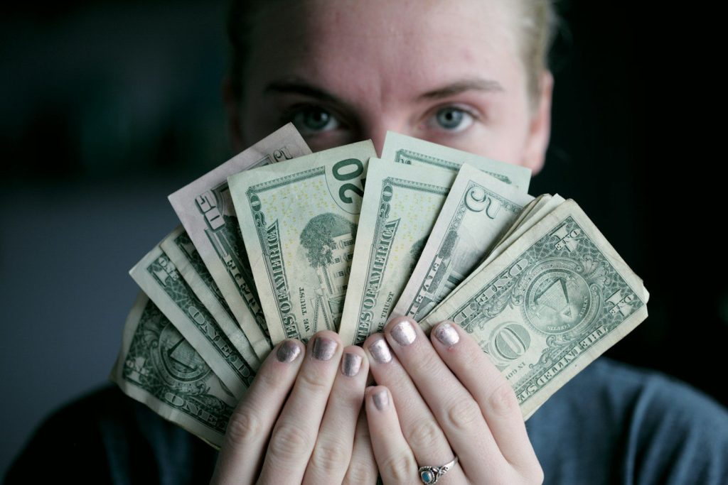 person holding fan of U.S. dollars banknote. Underrated Side Hustles for Women