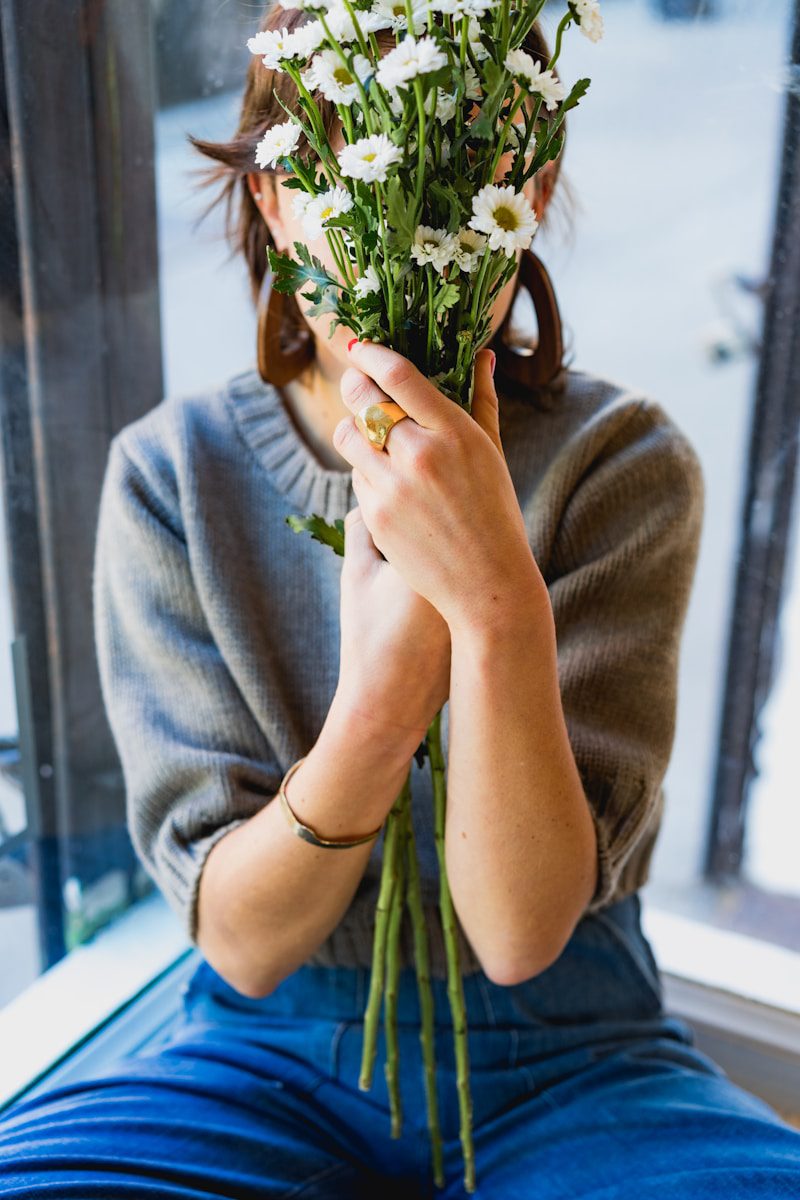 woman covering her face with white flowers - get creative indoors in January